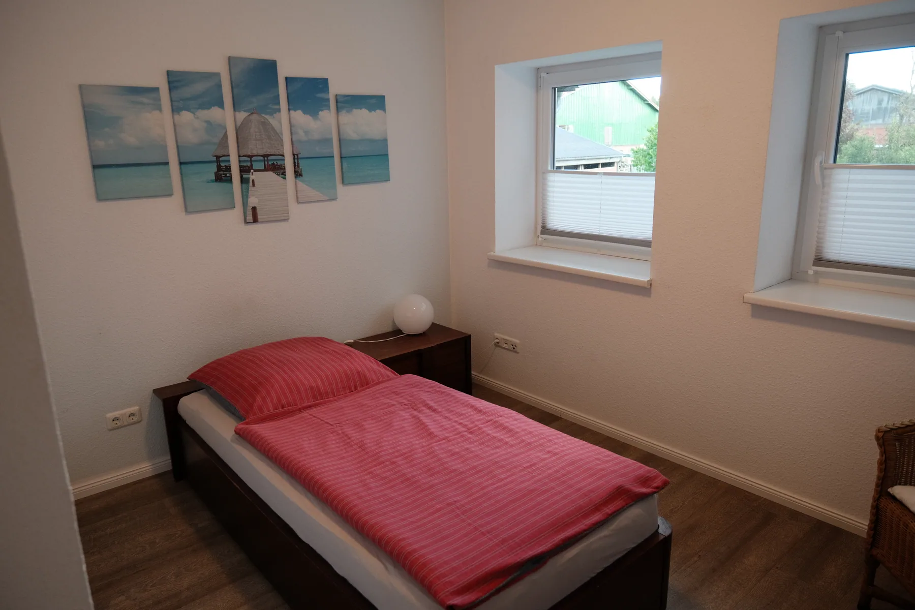 Einzelzimmer mit Einzelbett und zwei Fenstern